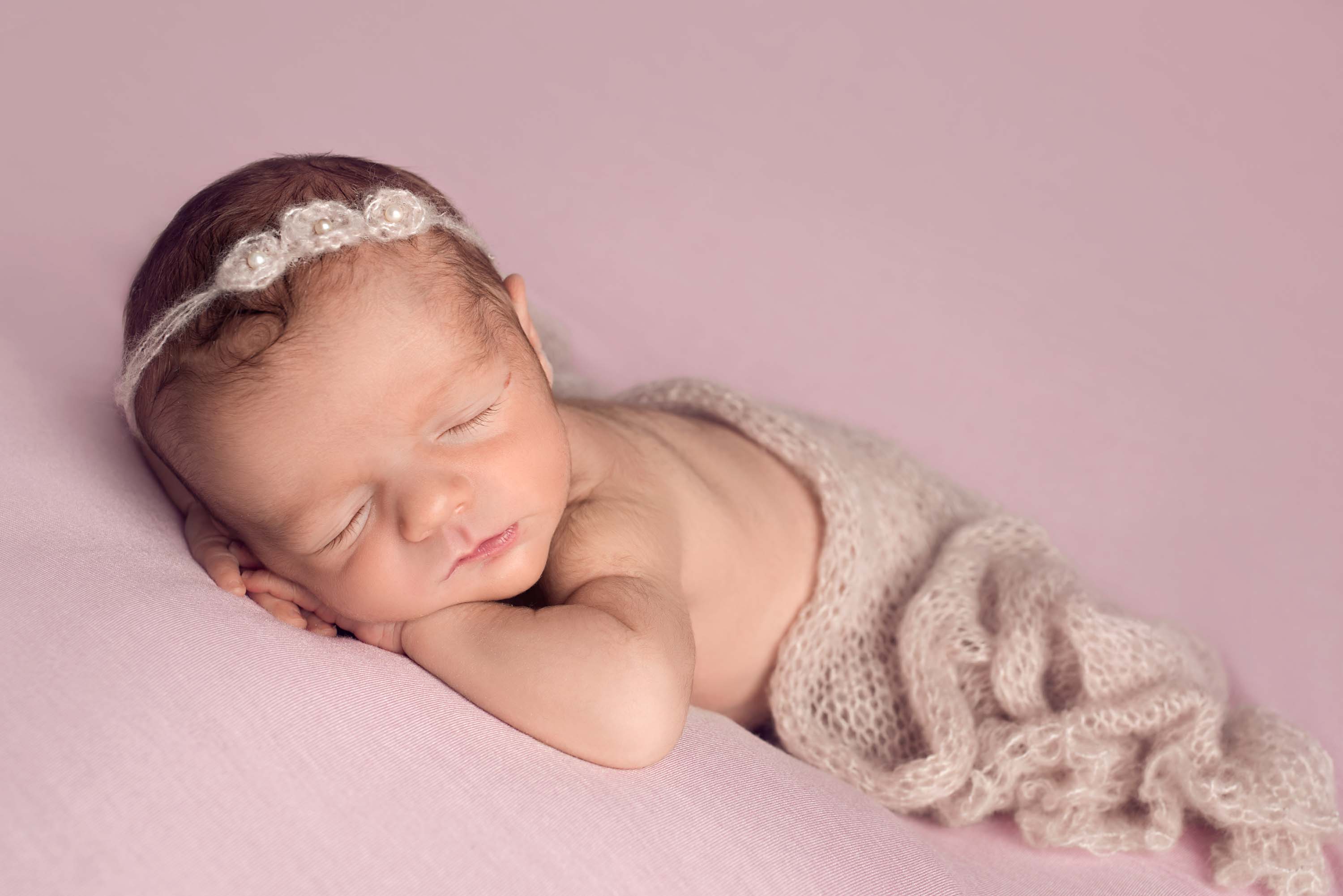 8 day old baby girl on pink blanket with dusty pink headband