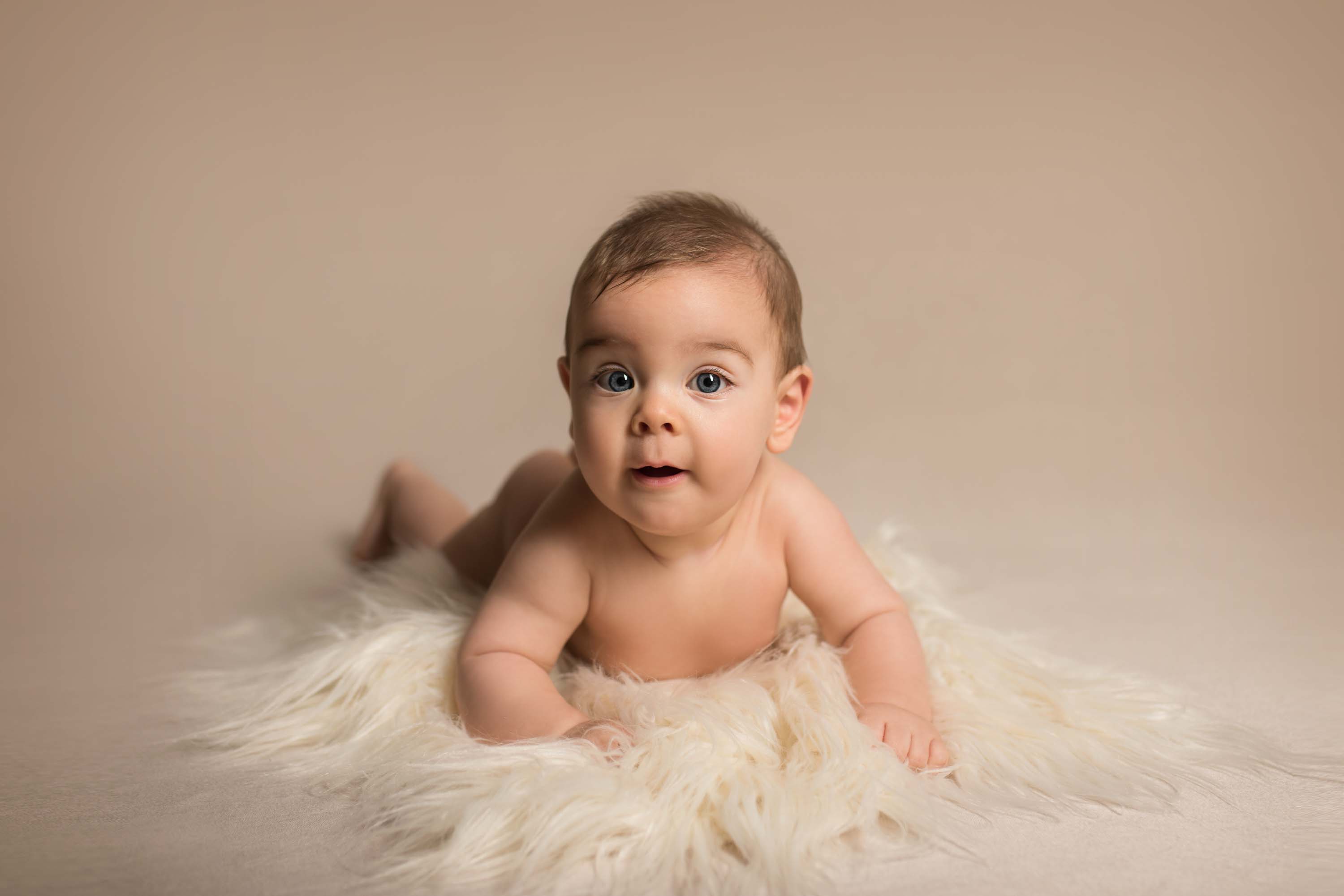 Baby boy doing tummy time on a fluffy rug during his sitter photoshoot