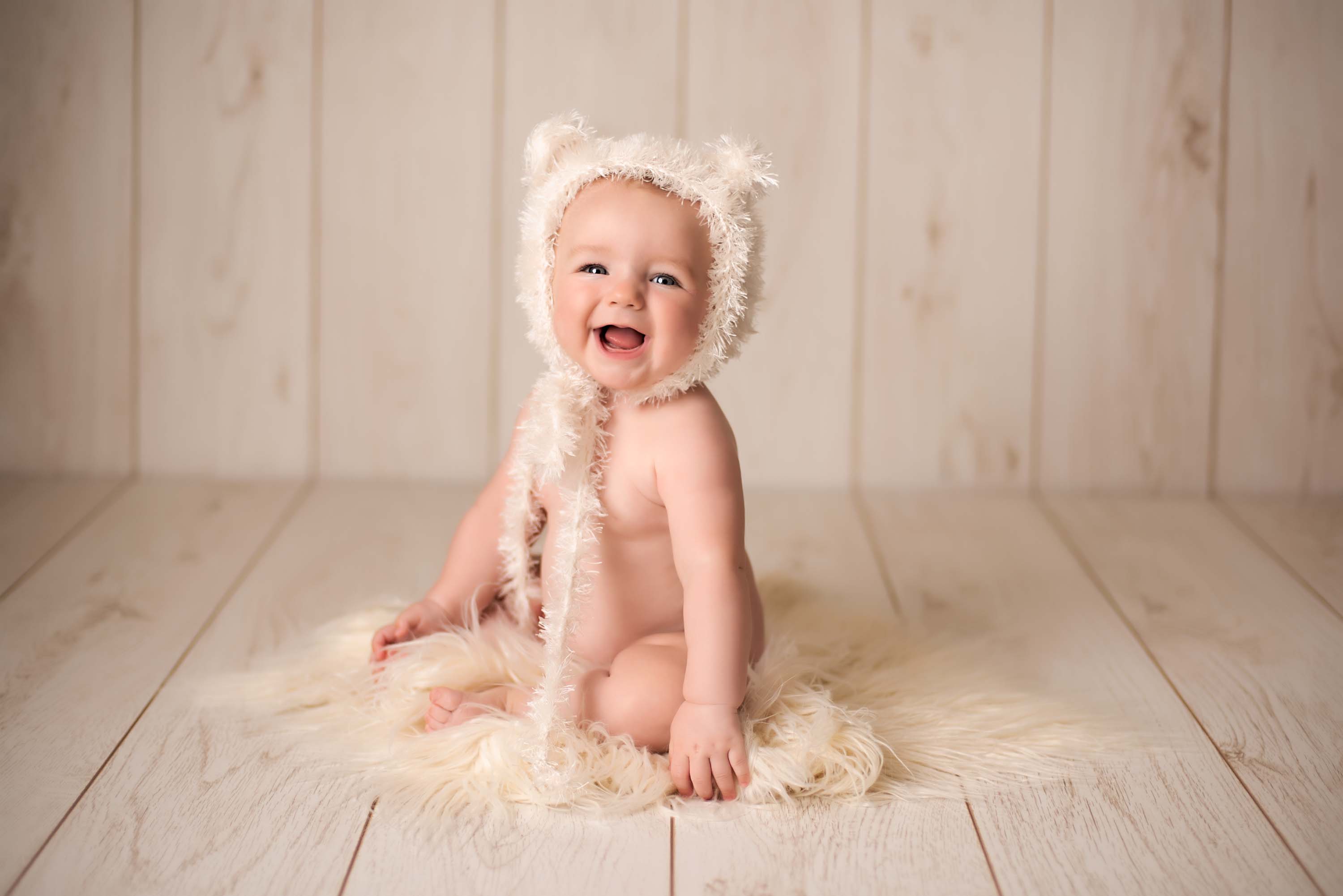 Baby girl wearing nothing but a fluffy knitted bear hat