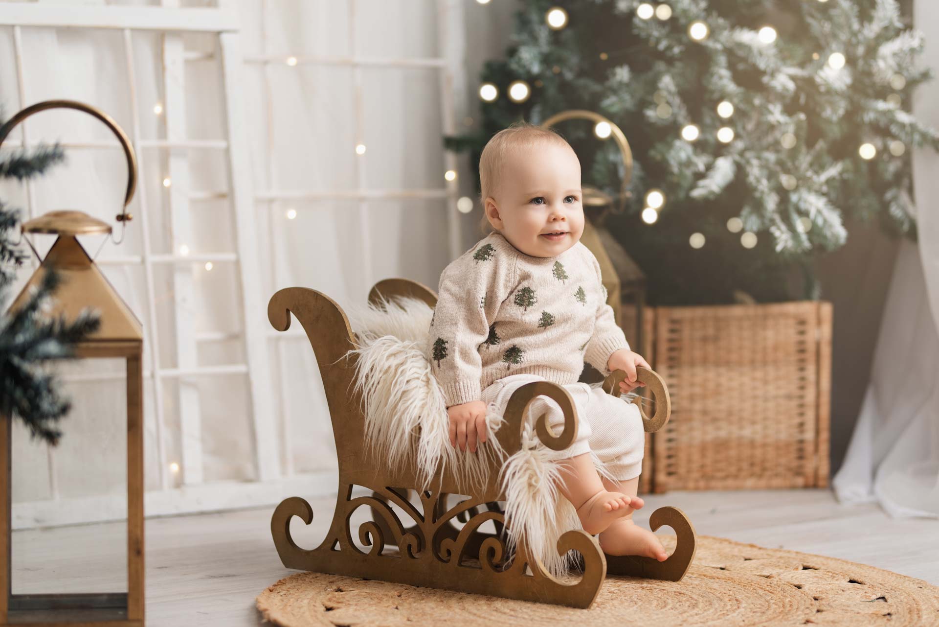 Baby Christmas Photo Shoot Oxfordshire One year old boy sitting in a wooden sleigh for his baby Christmas photoshoot