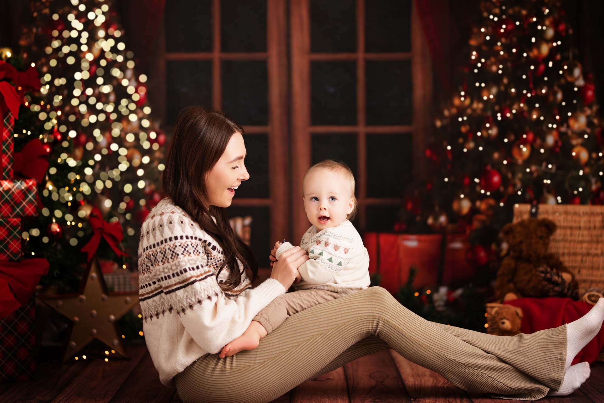 Family Christmas Photos Oxfordshire A mother has her son on her lap playing row your boat at their Christmas photoshoot