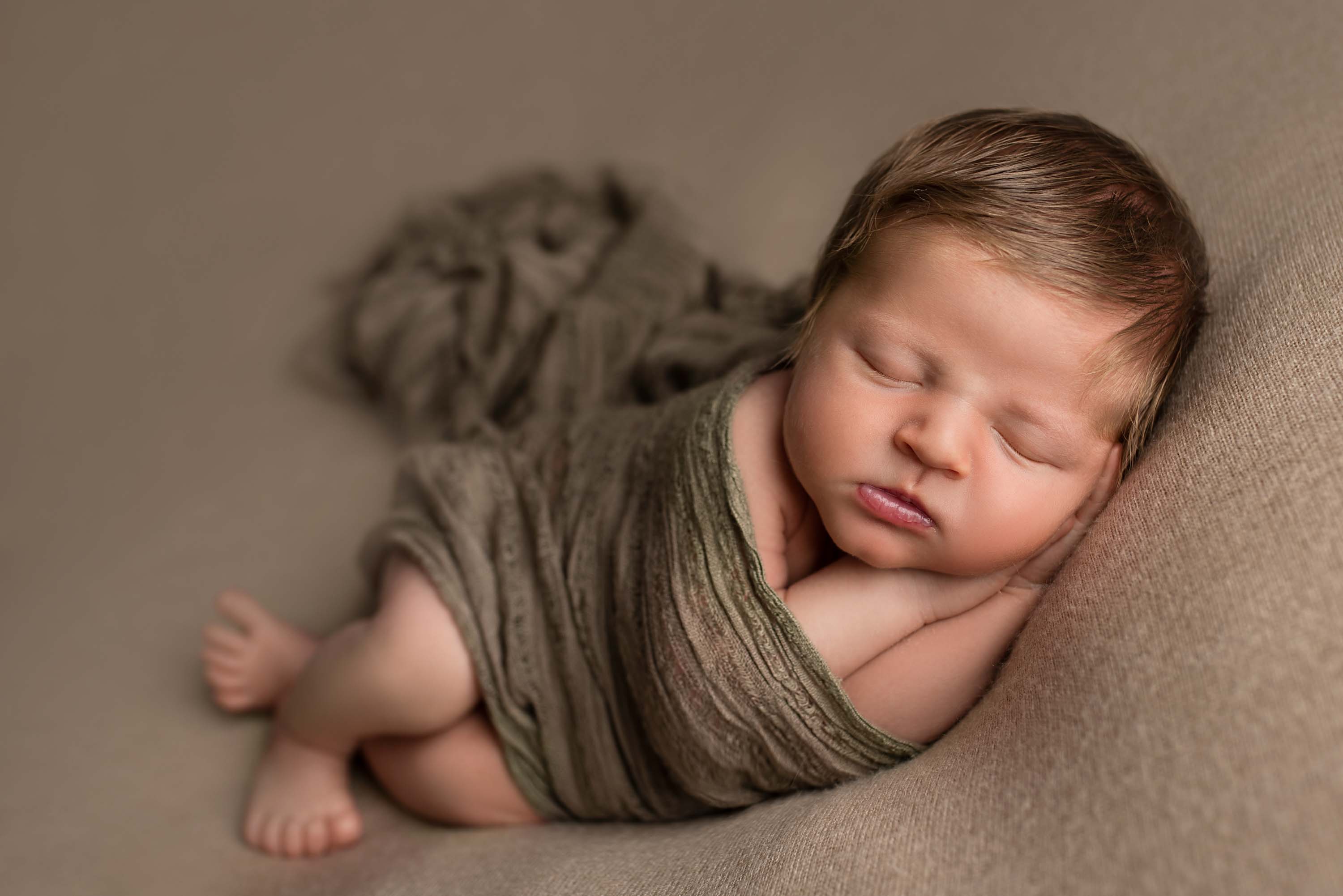 Baby boy with fine head of hair asleep during his baby photo shoot