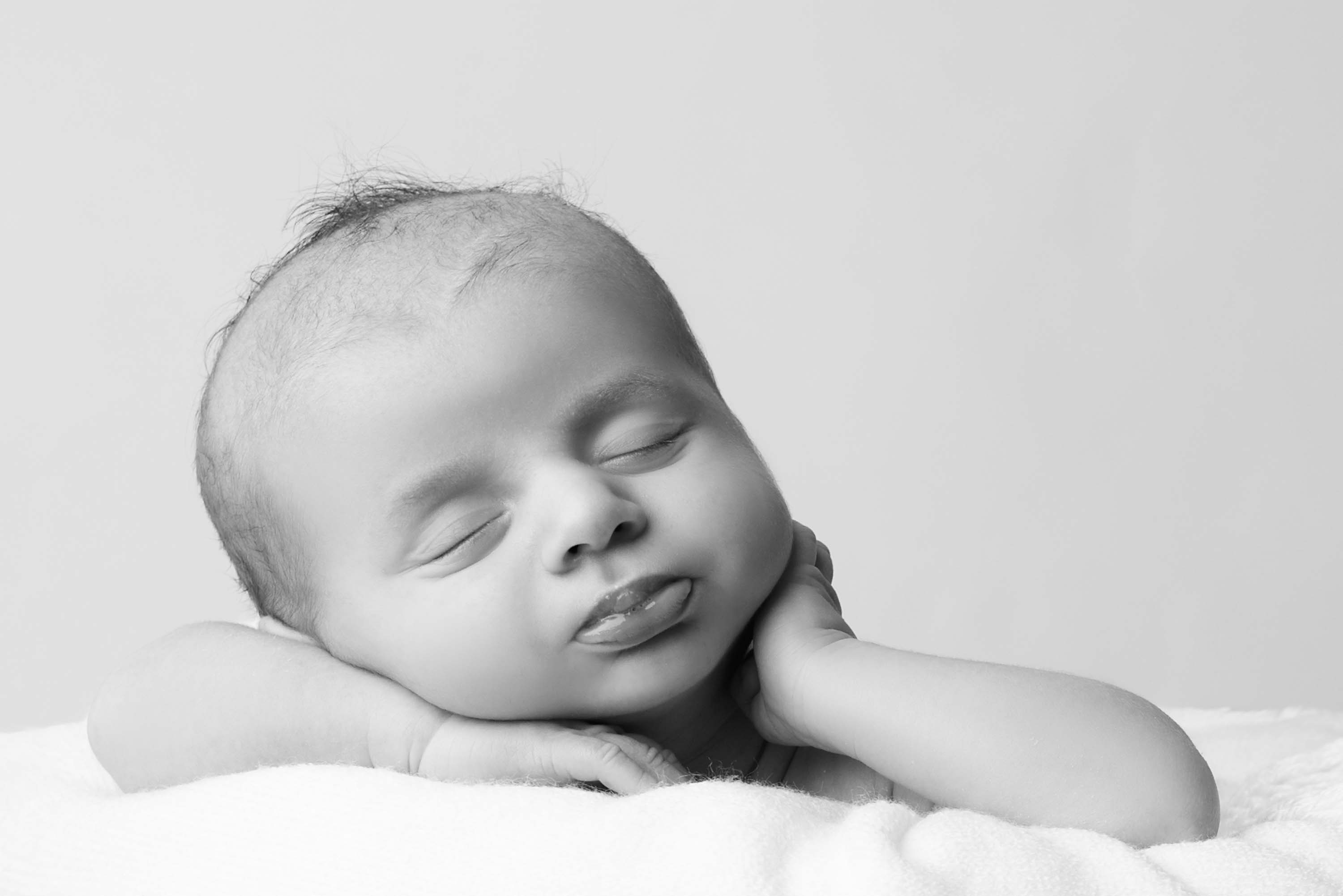 Month old boy looking chilled out, asleep with his head on his arms