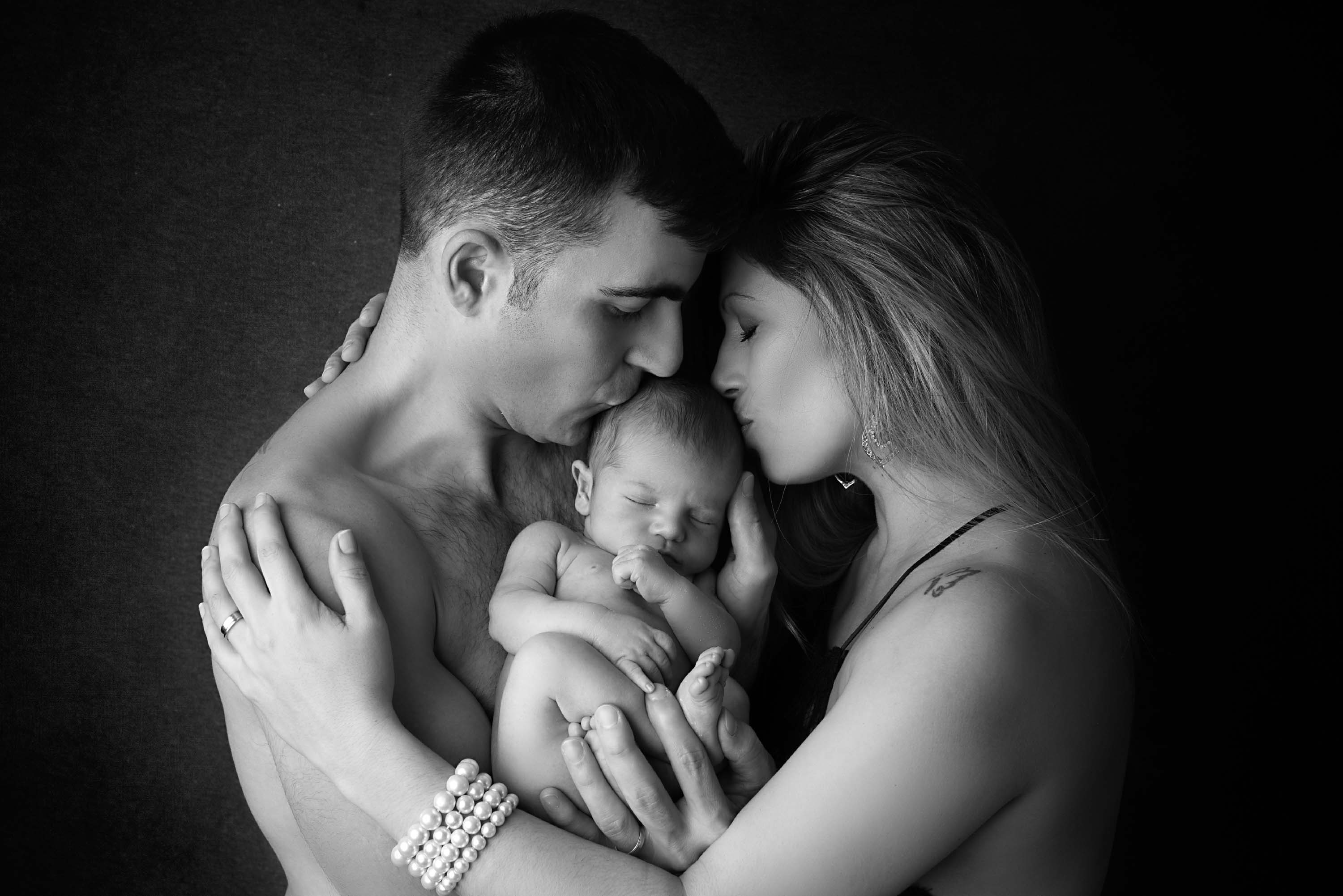 New parents both kissing their boy on the head