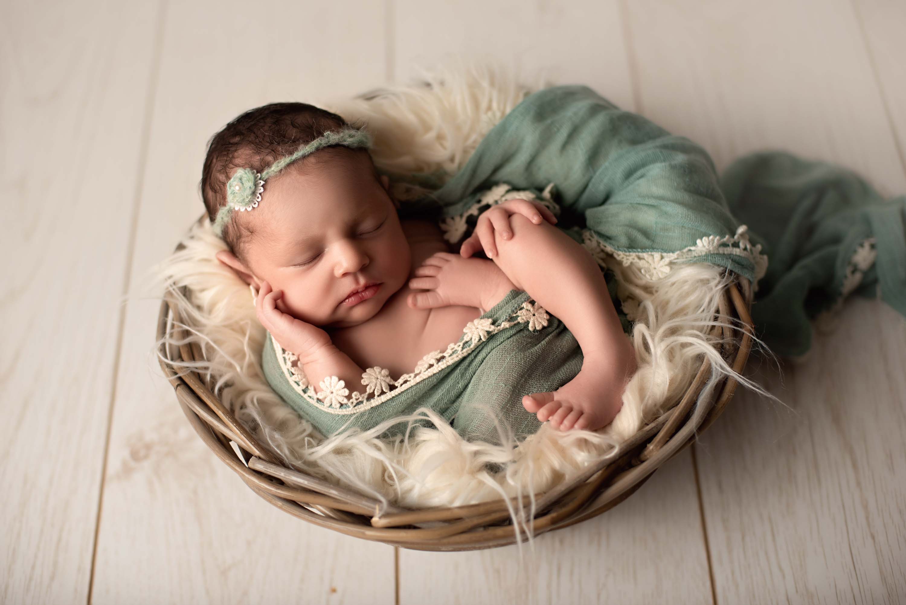 Week old baby girl sleeping in a basket for her newborn portraits