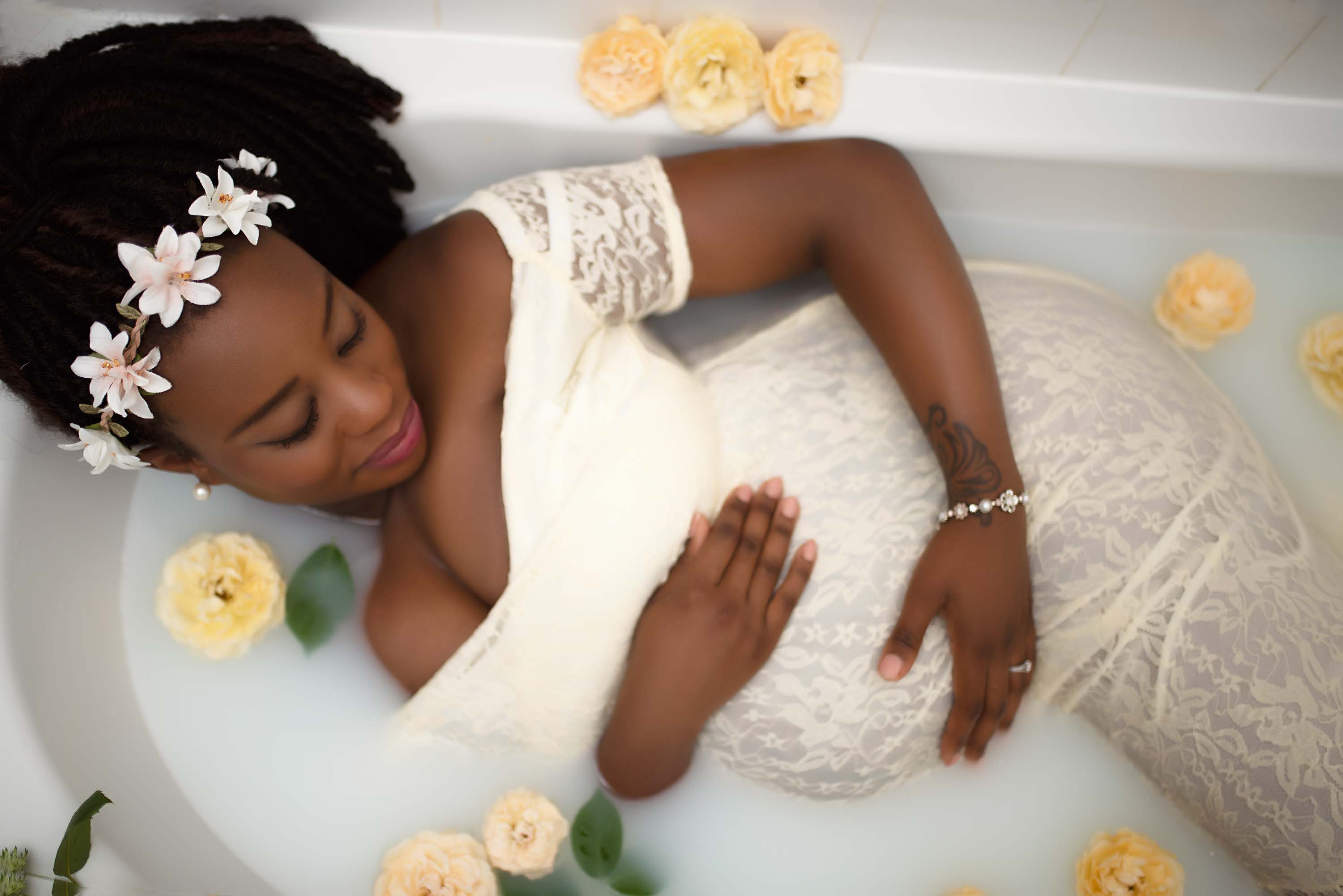 Women wearing maternity dress and floral crown in milk bath