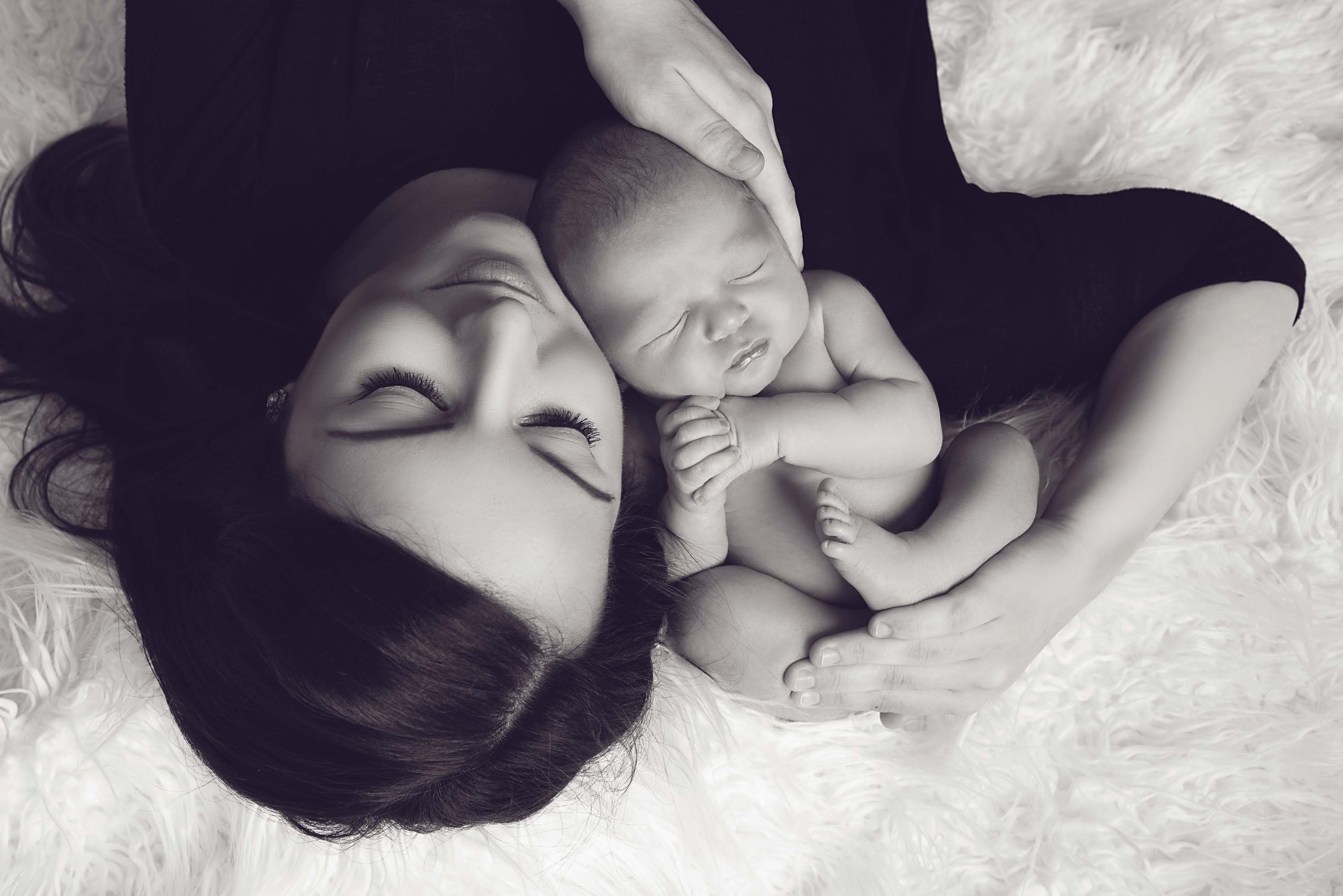 New mum lying down holding her baby boy at their newborn photoshoot