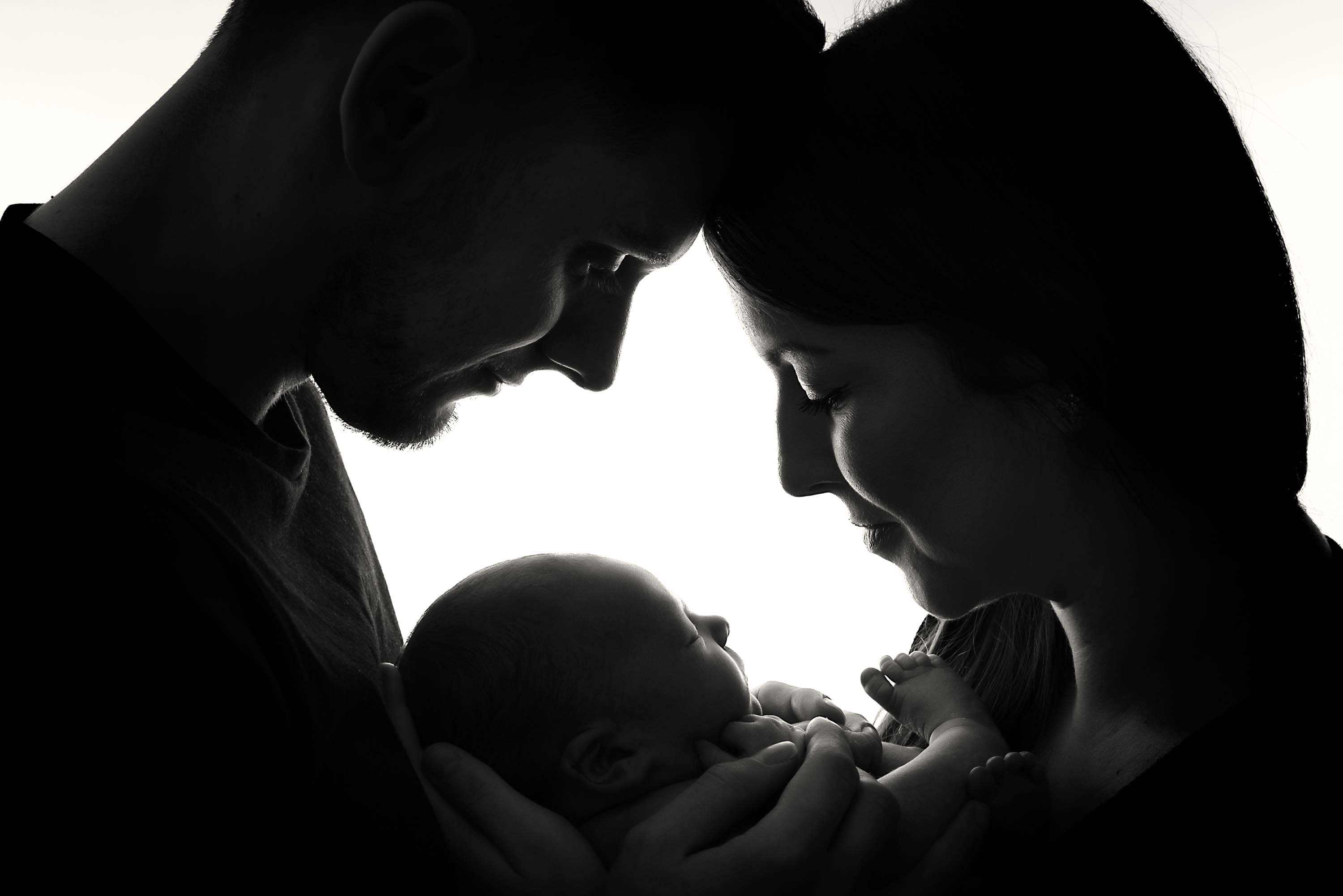 Silhouette of new parents smiling at their baby