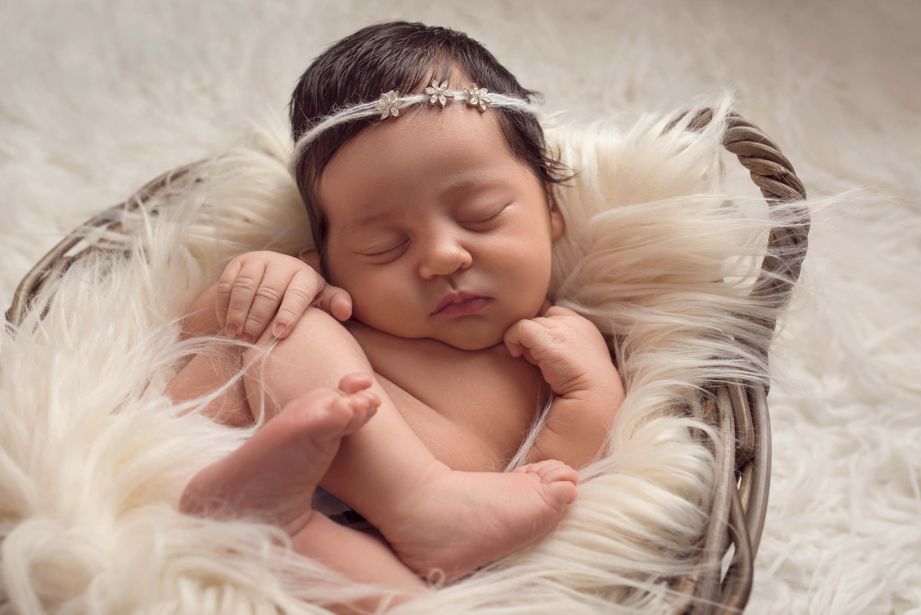 Baby girl holding her knee fast asleep at her photo shoot