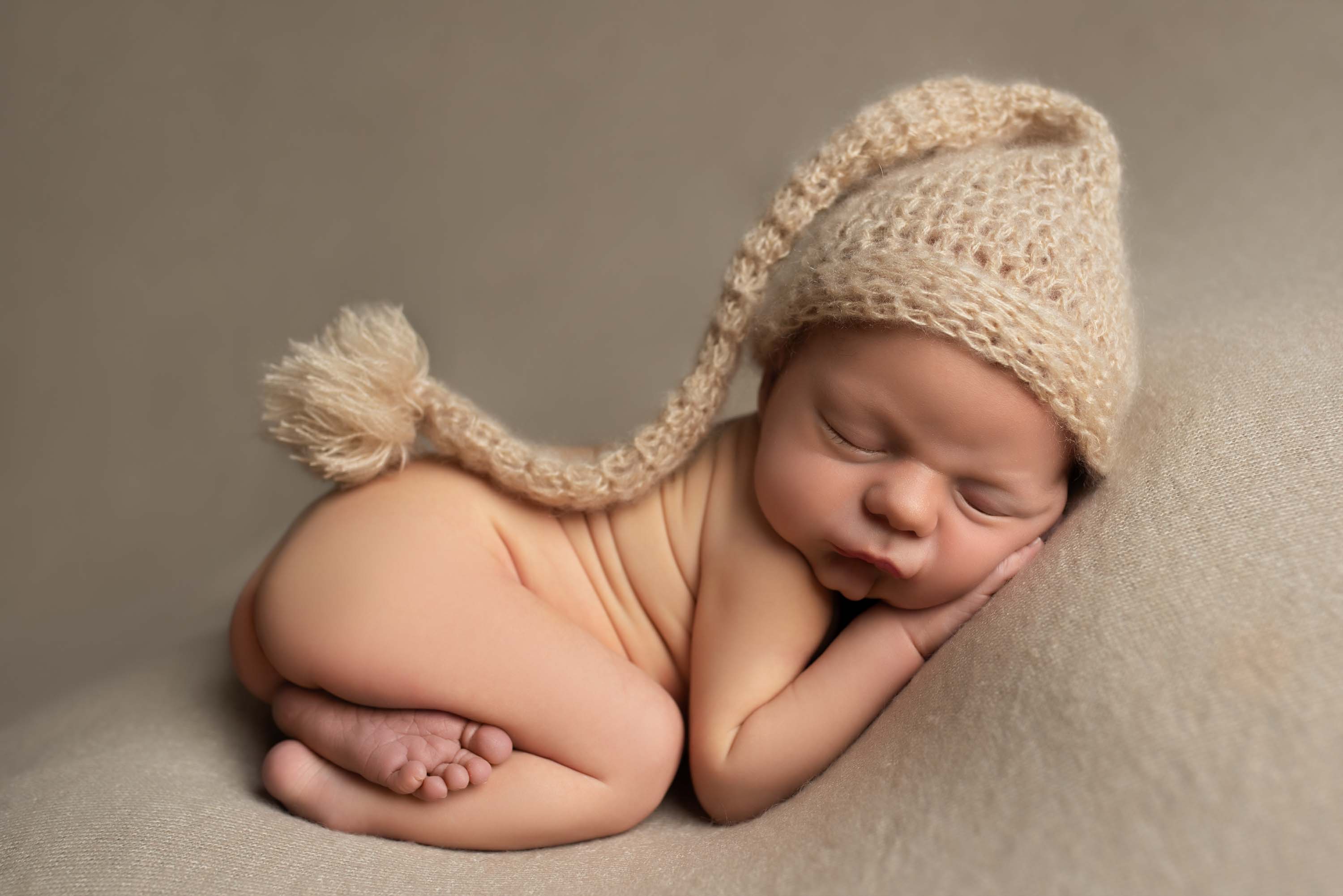 Newborn baby boy in tushee-up pose with long knitted hat