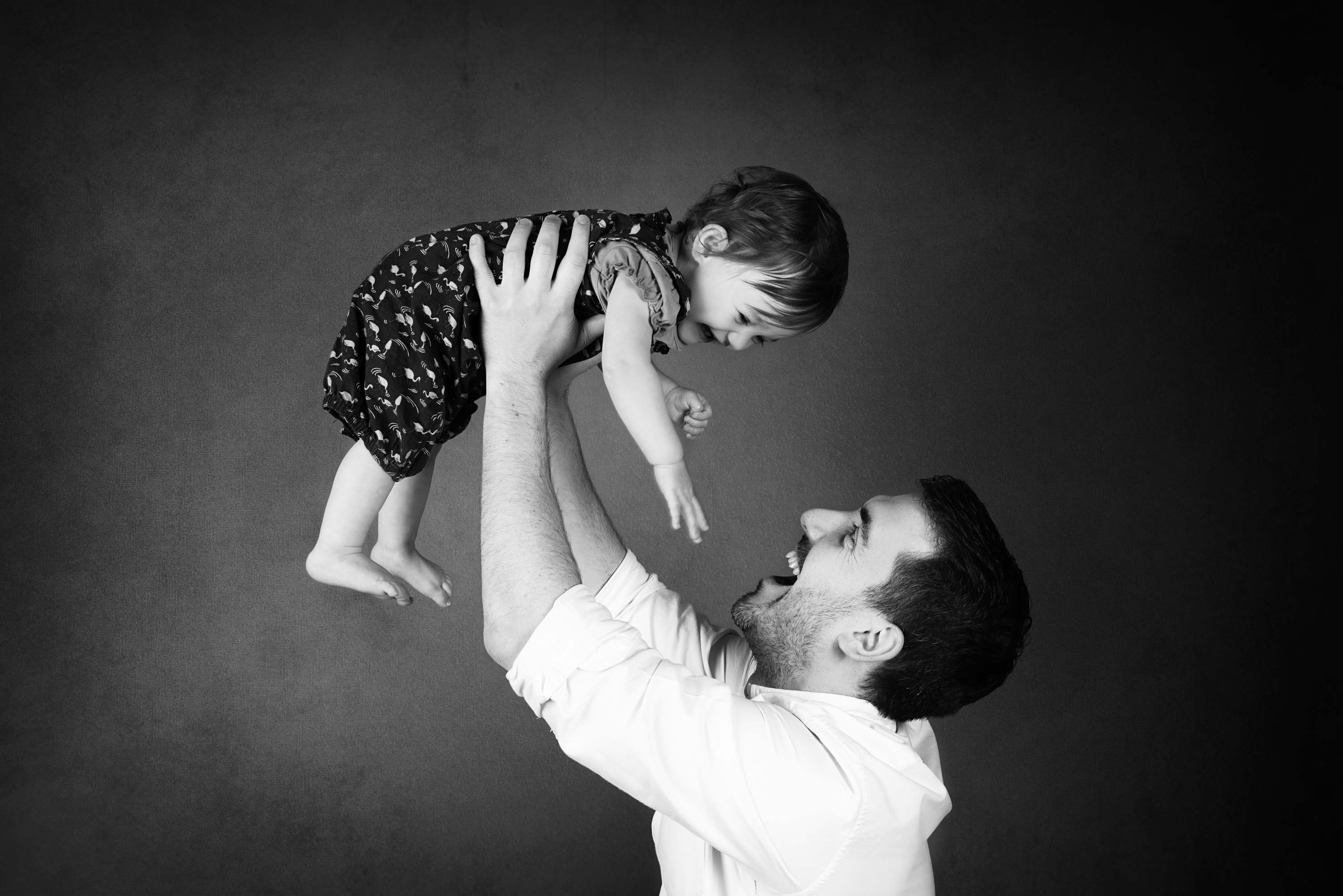 Father throwing his daughter in the air at her first birthday photoshoot