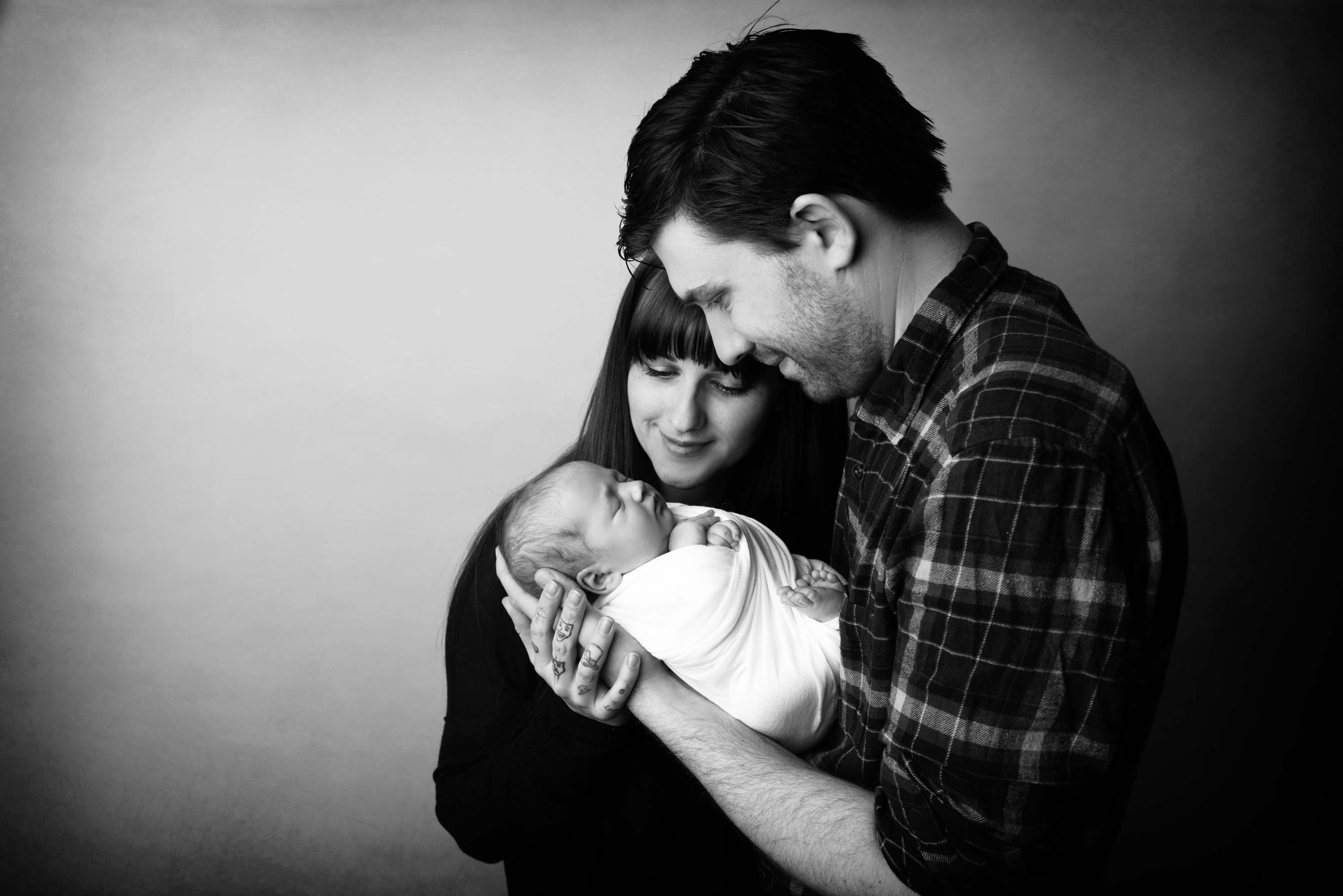 Black and white of a young couple looking adoringly at their newborn baby