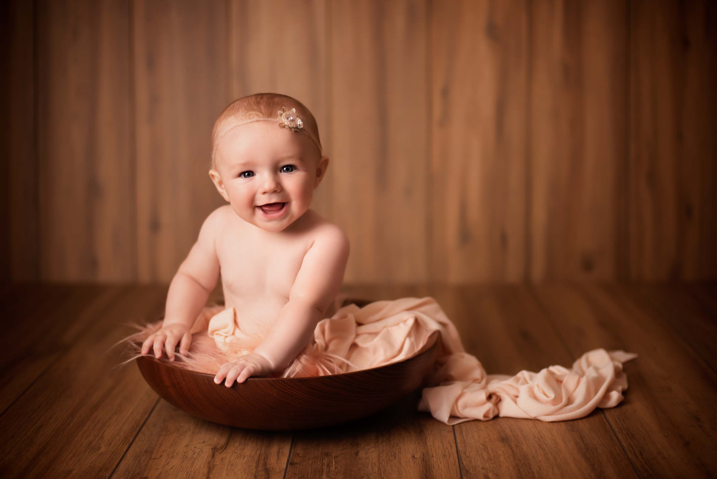 Little girl sitting in bowl and smiling at the photographer