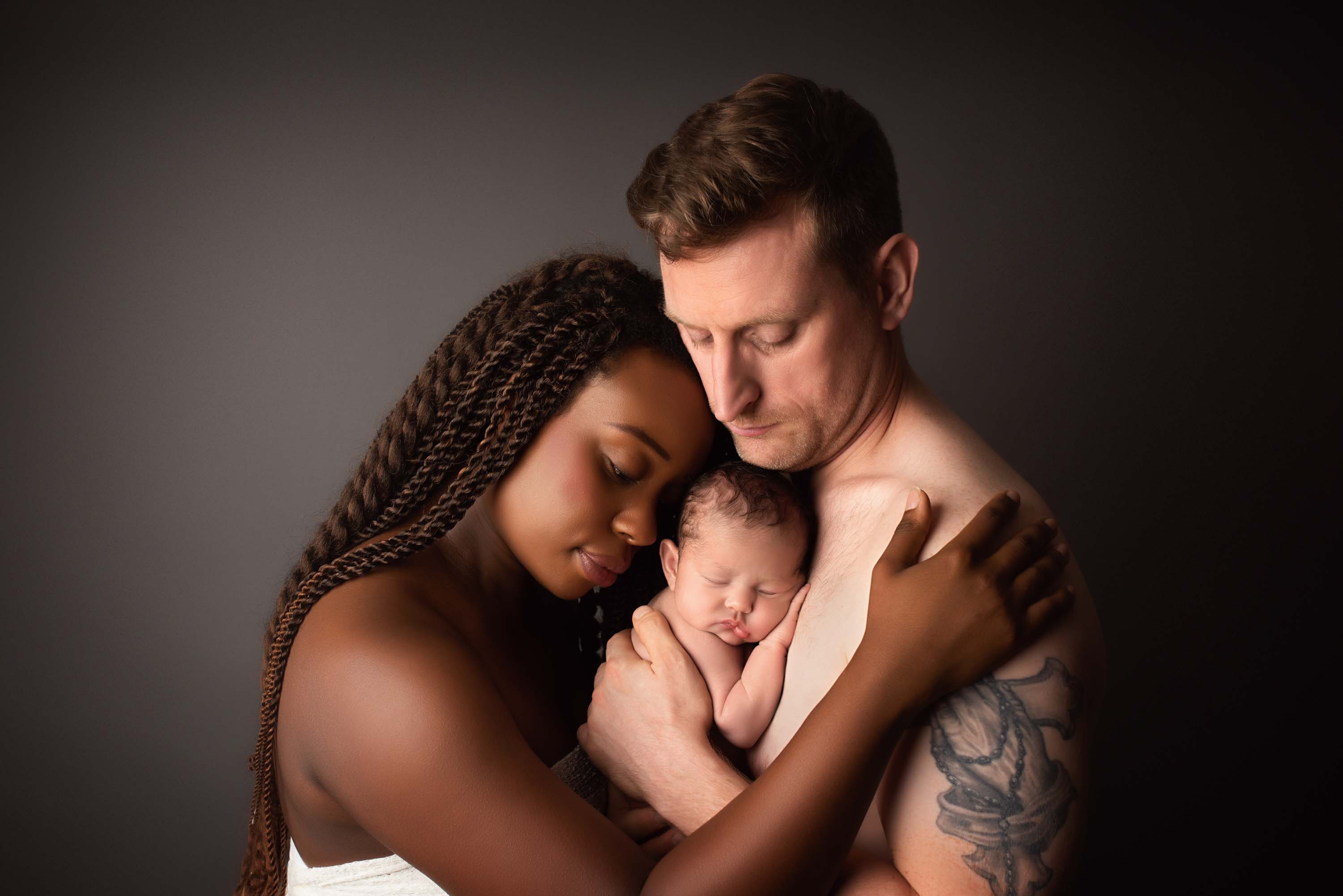 Couple embracing their newborn baby at their baby photography session