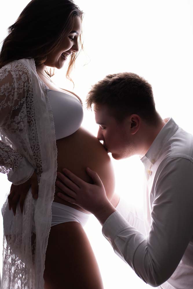 Daddy-to-be kissing his pregnant partner's bump