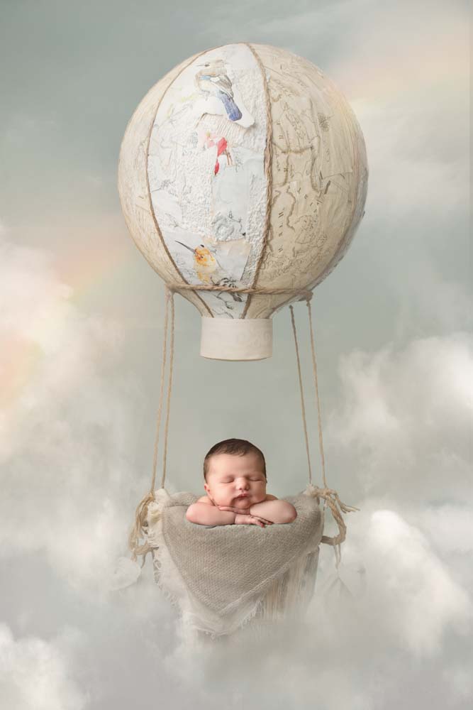 Newborn boy floating in a vintage hot air balloon