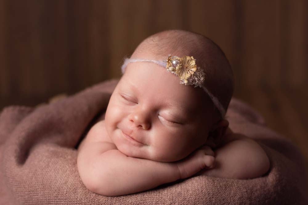 Baby girl smiling at her newborn photoshoot