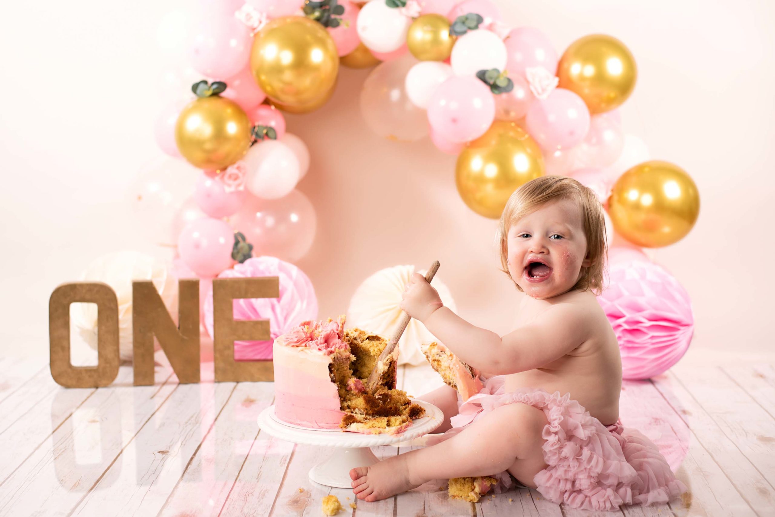 Girl smashing cake with wooden spoon