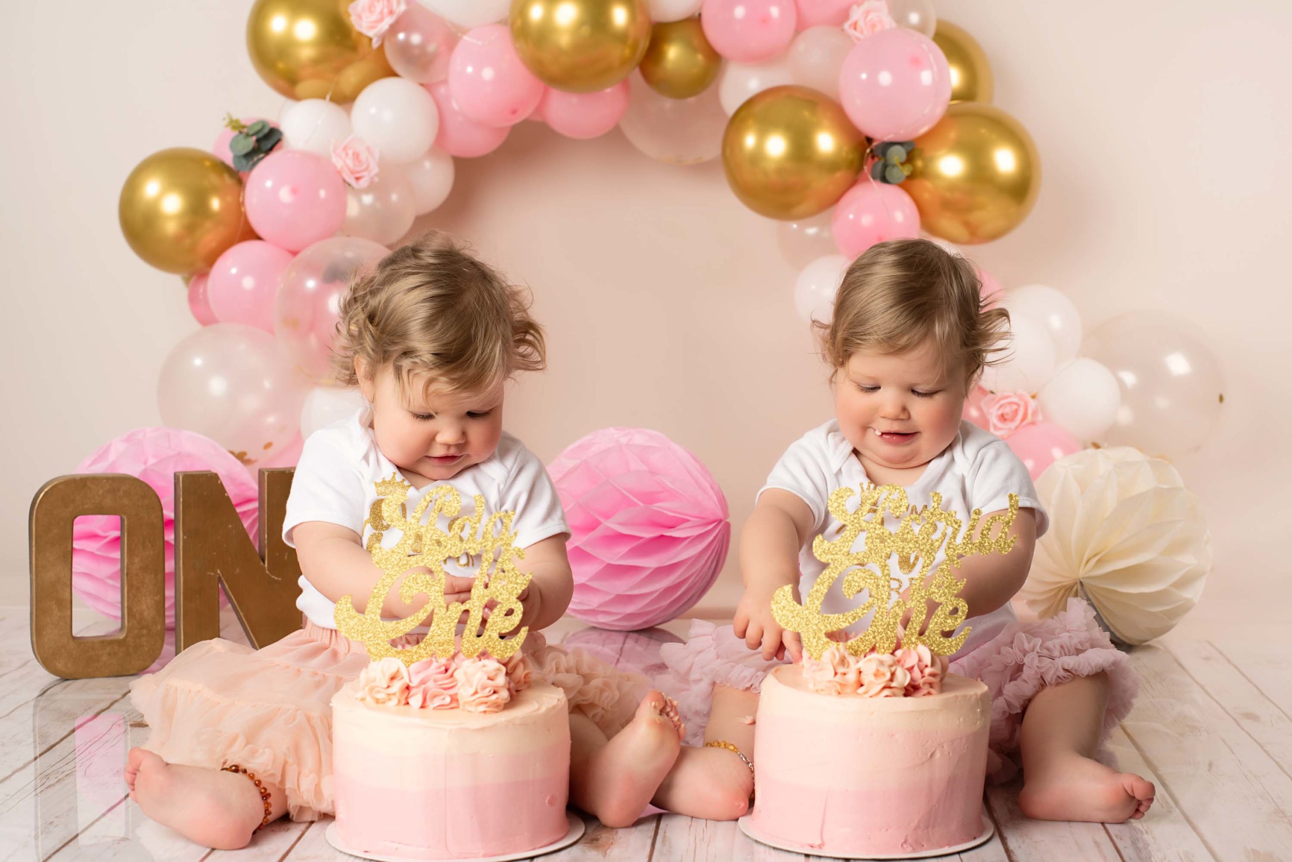 Twins babies getting stuck into cakes at their photoshoot
