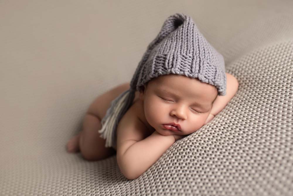 Baby boy asleep on photographers beanbag wearing sleeping cap
