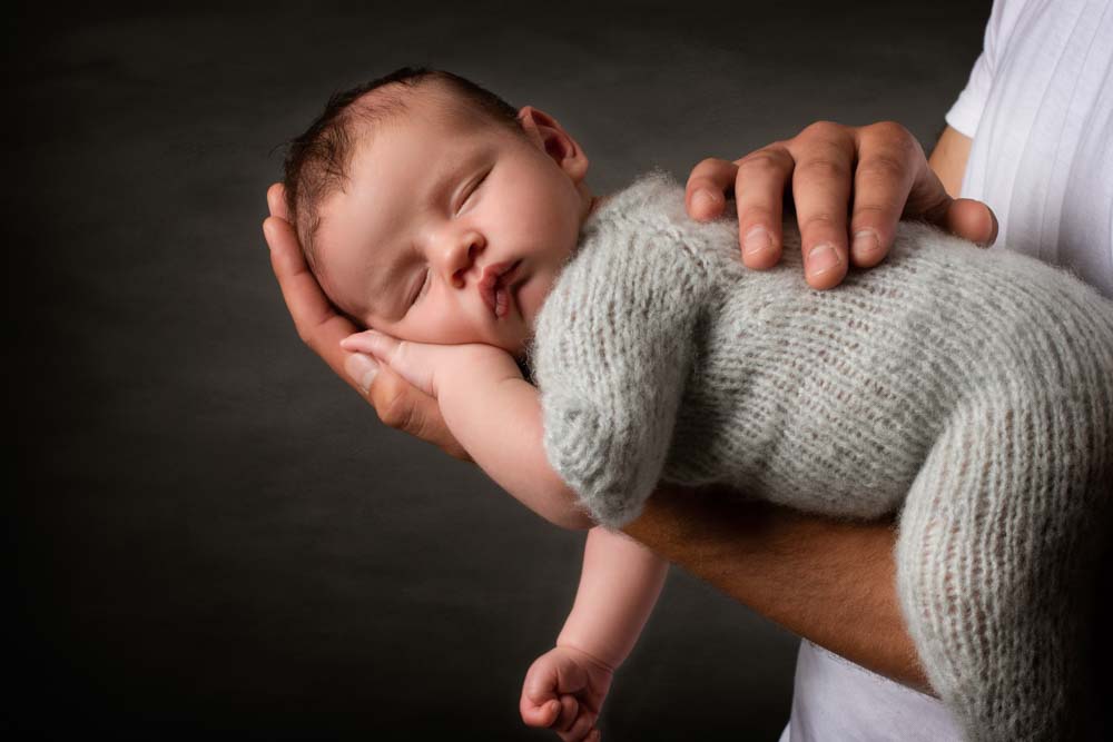 Newborn baby boy asleep on daddy's arm