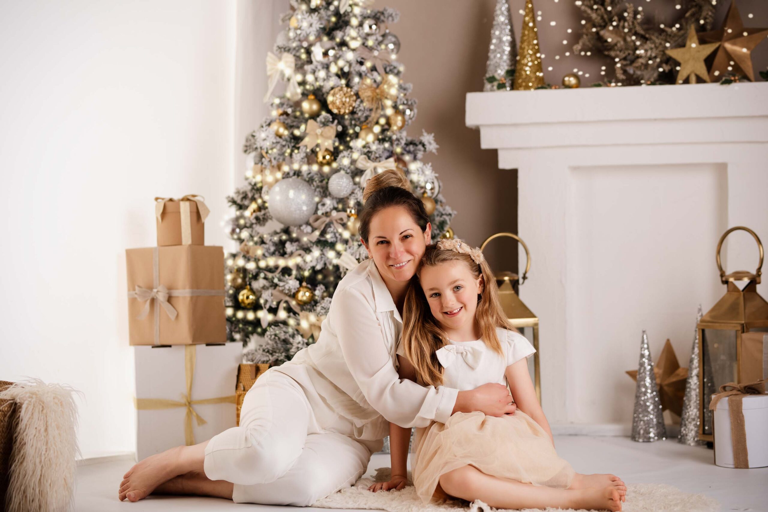 Mother and daughter sitting in front of a Christmas tree at their annual photoshoot