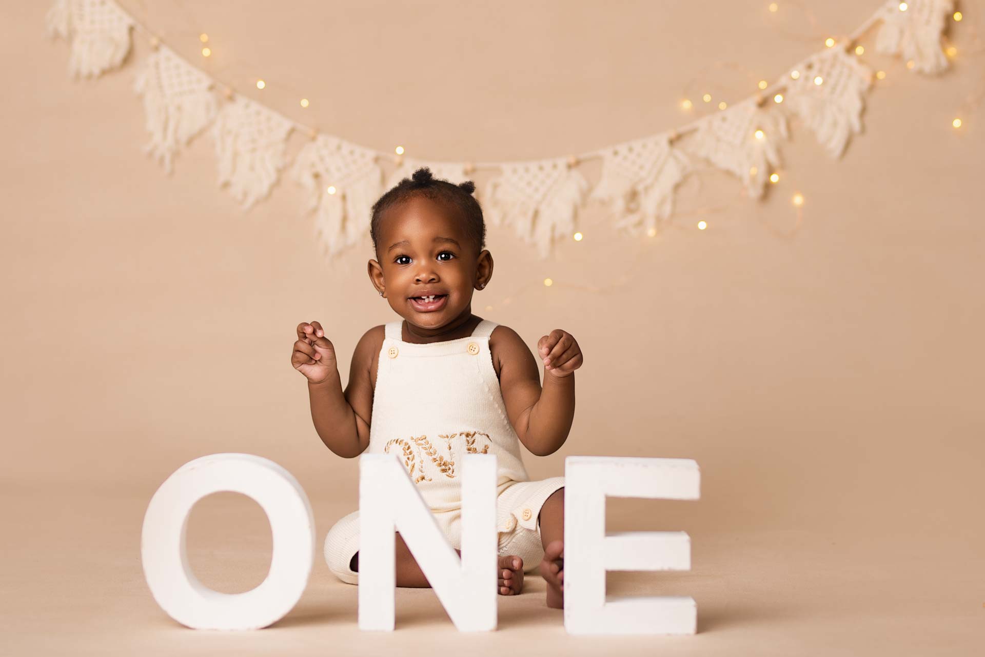 Birthday cake sitting behind the letters ONE at her photoshoot