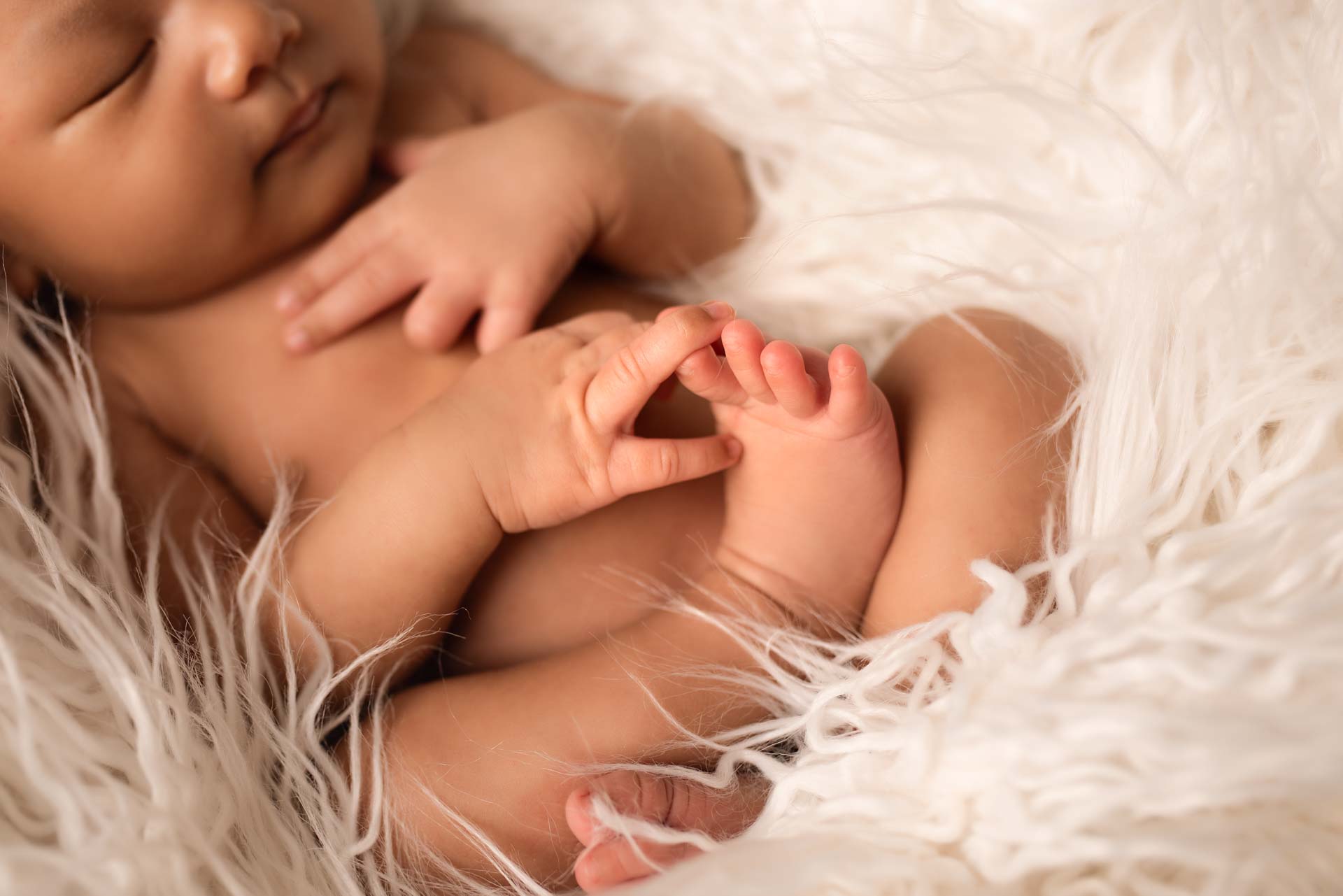 Sleeping baby holding their tiny toes
