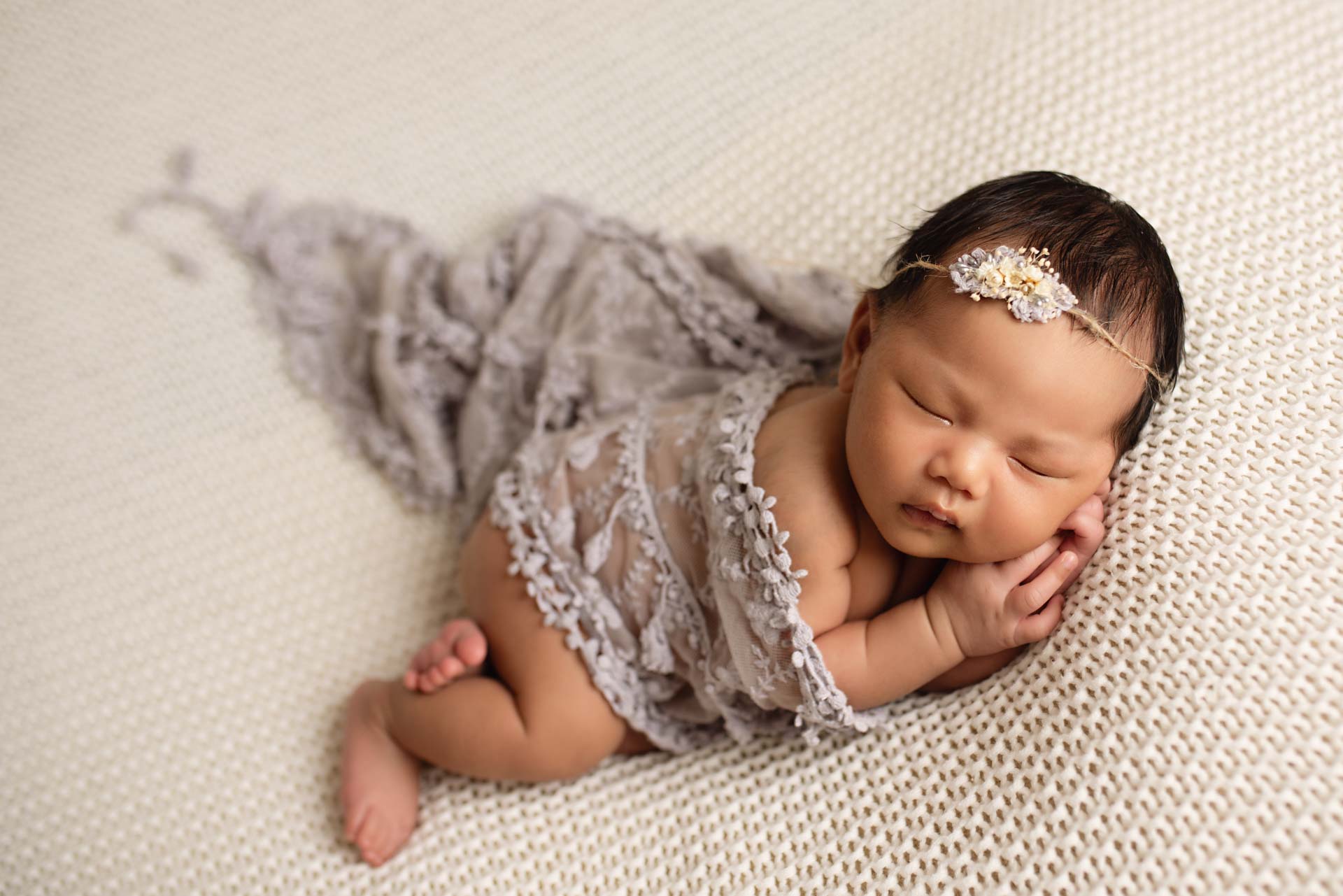 Baby girl covered with a lace shawl wearing a delicate headband