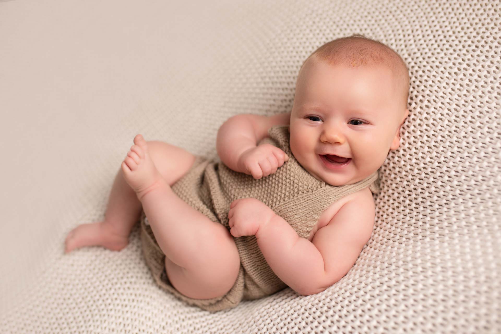 Laughing newborn baby interacting with the photographer at her photoshoot