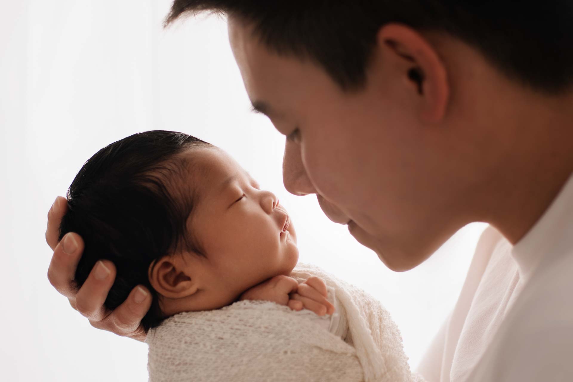 New father holding his daughter with their noses almost touching.