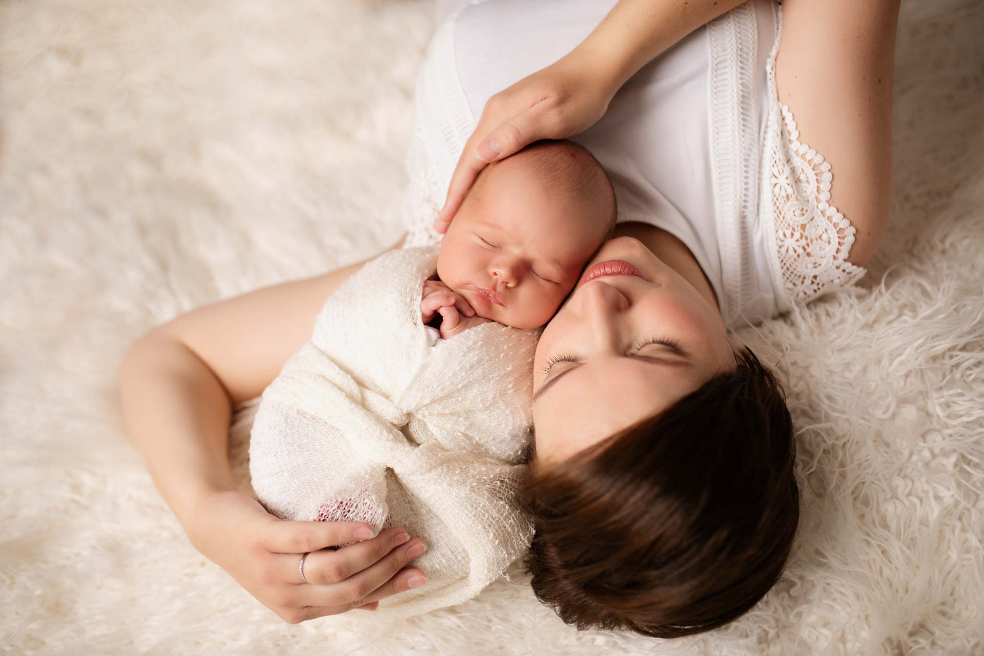 Newborn baby boy swaddled being cuddled by his mother