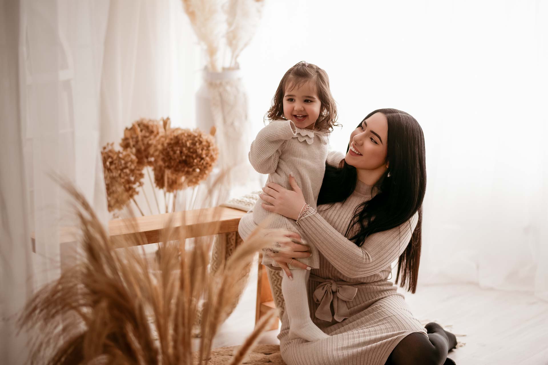 Mother and daughter sitting on the floor next to a bench in the family photography studio