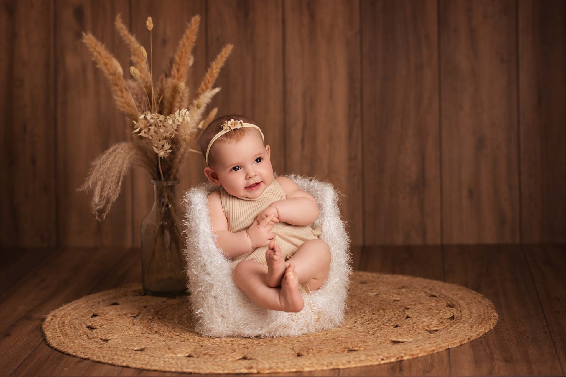 Girl sitting in the photographers unique pod chair. In the backgroud are dried flowers and dark wooden floorboards.