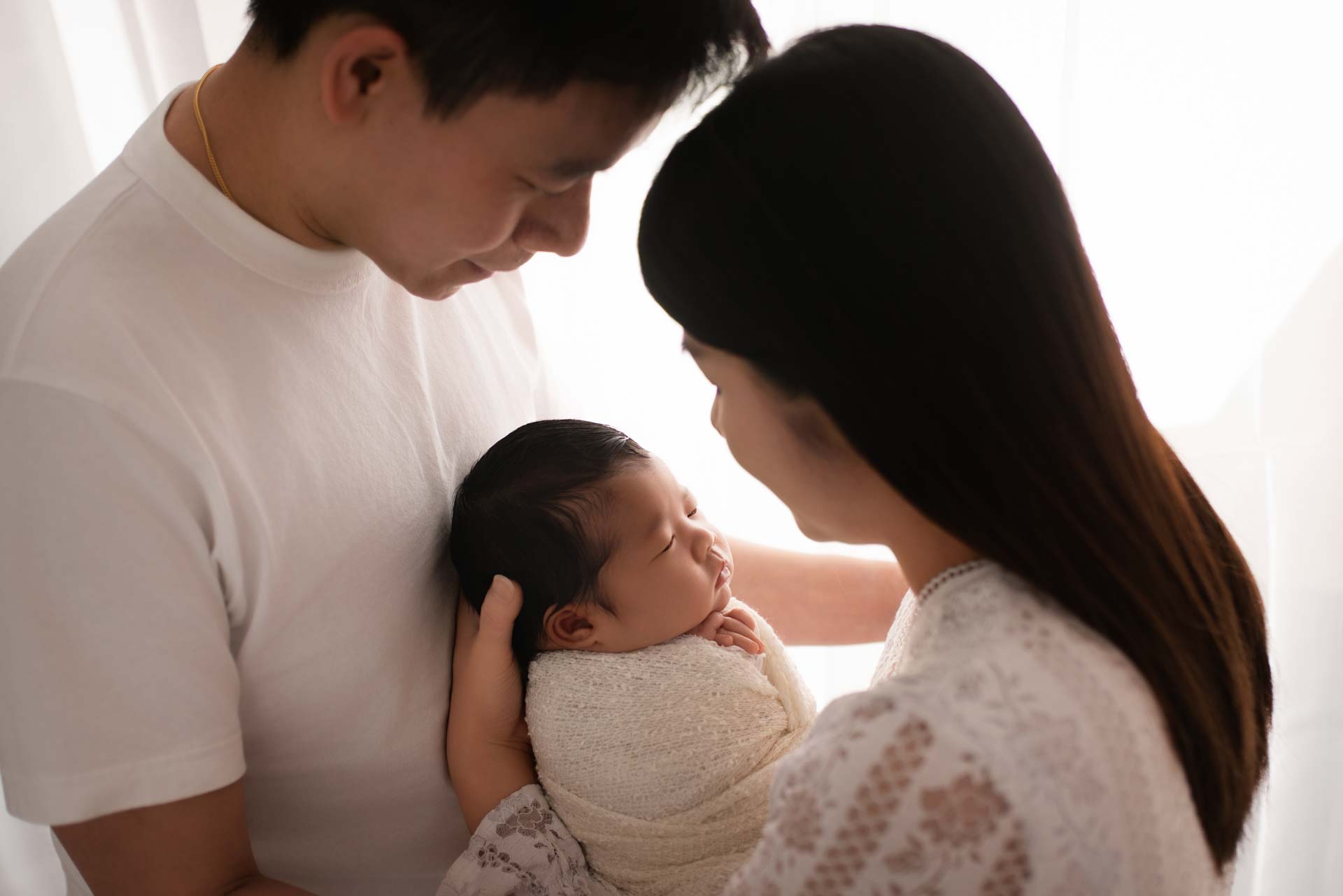 Mum and Dad head to head with their newborn daughter in between them