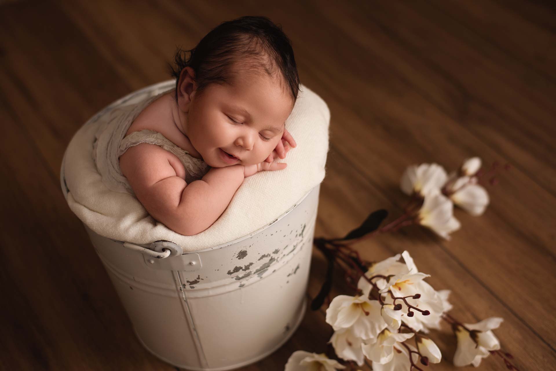 Baby posed in a white bucket surround by white flowers