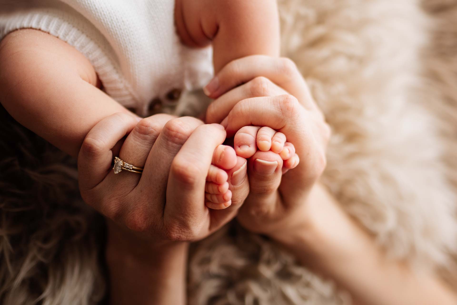 A mother's hands embracing her newborn baby's feet