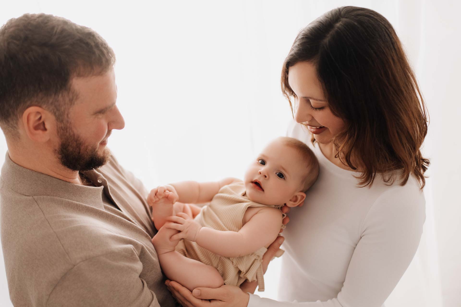 Mother and father holding their new baby between them
