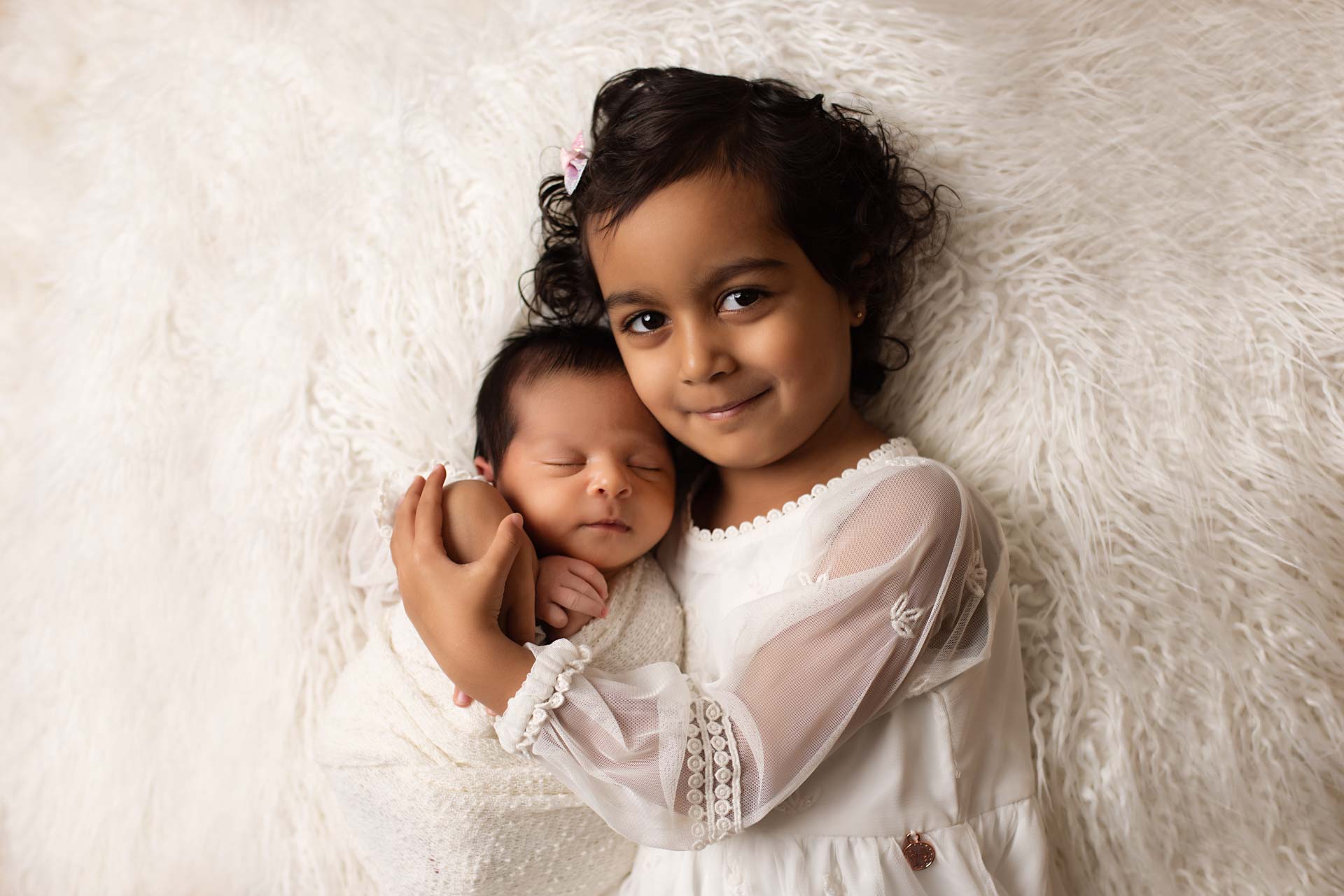 Big sister giving her newborn sibling a cuddle