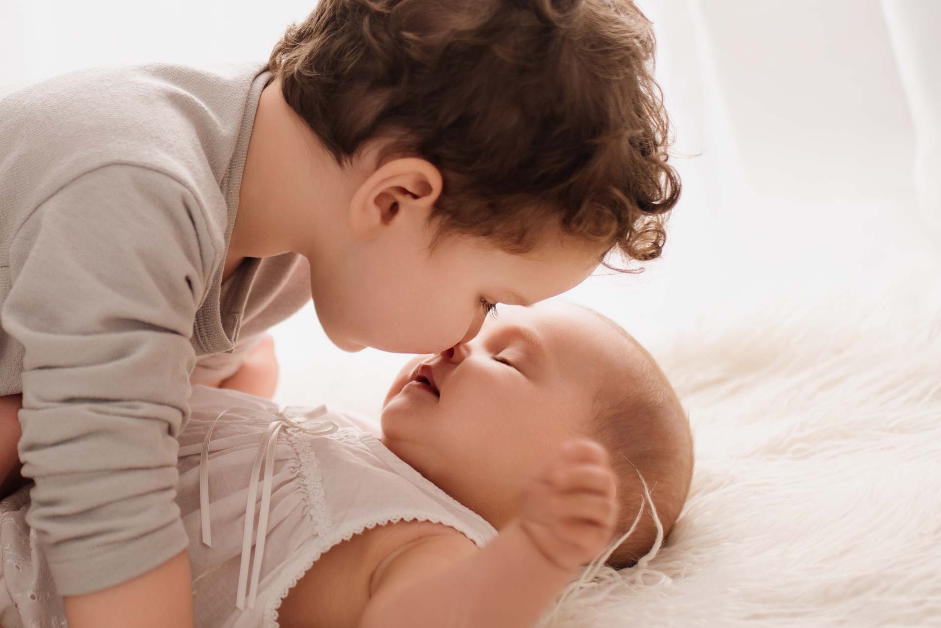 Little boy nose to nose with his newborn sibling