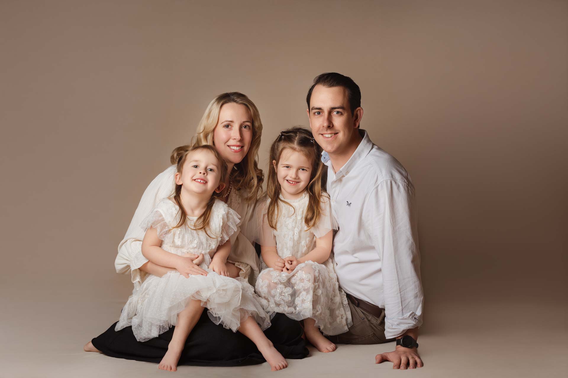 Family of four sitting in the photographers studio for their family photoshoot