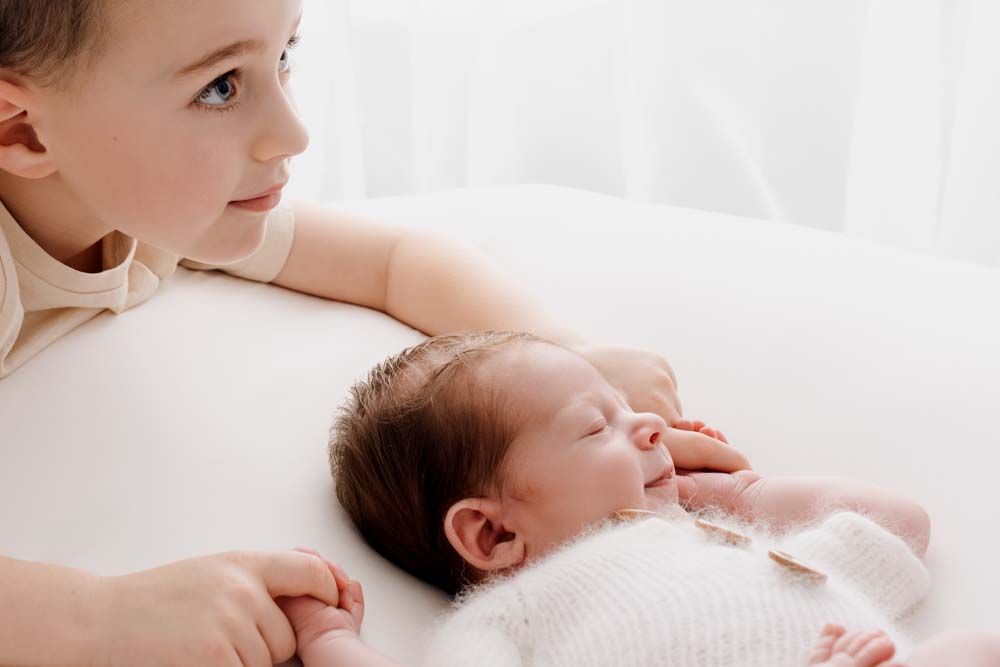 Siblings being photographed during a newborn photoshoot