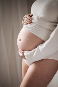Close-up of a pregnant lady's bump with the window light highlighting the shape