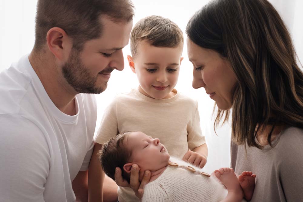 Parents and sibling look adoringly at the new baby boy