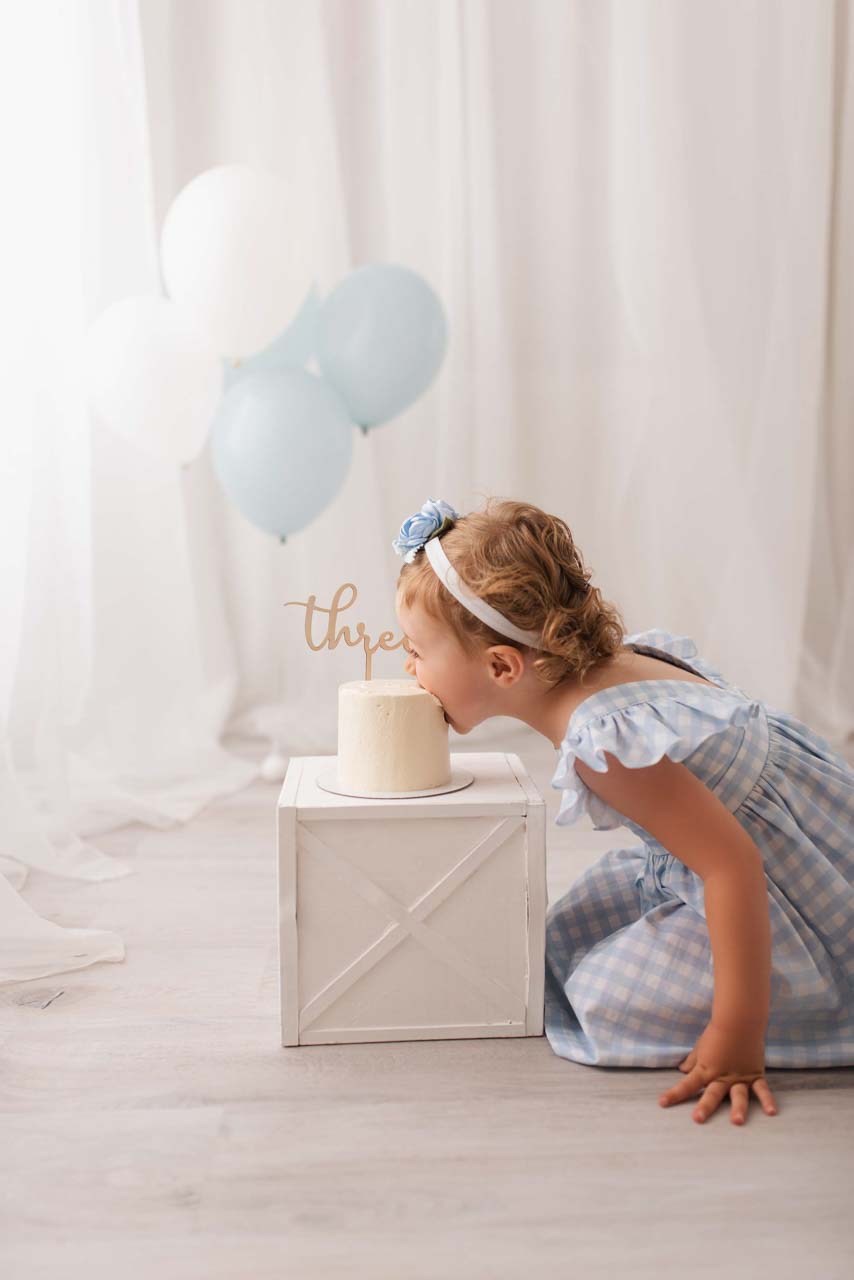 Young girl going face first into her birthday cake