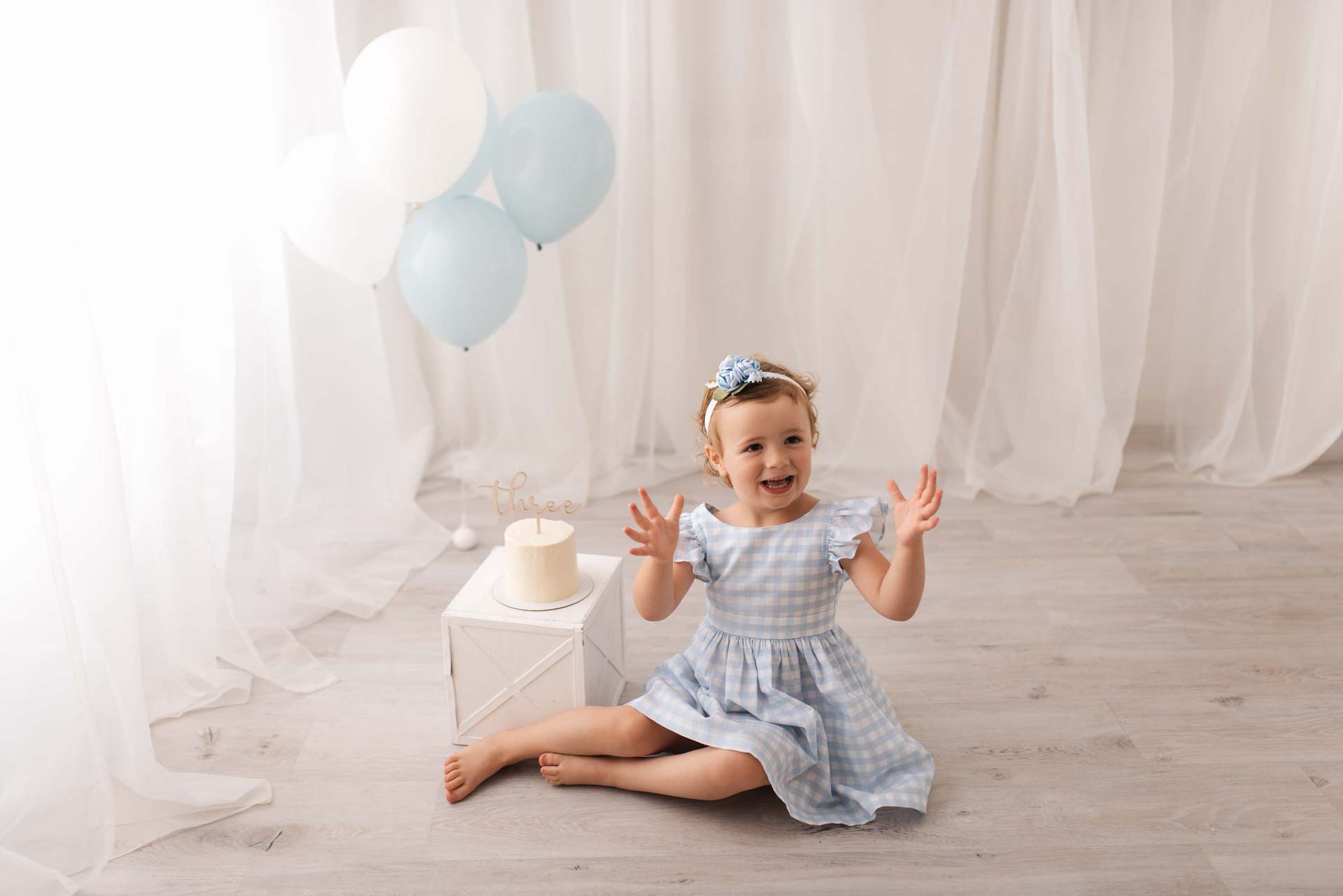 Three year old celebrating her birthday in a blue and white themed setup