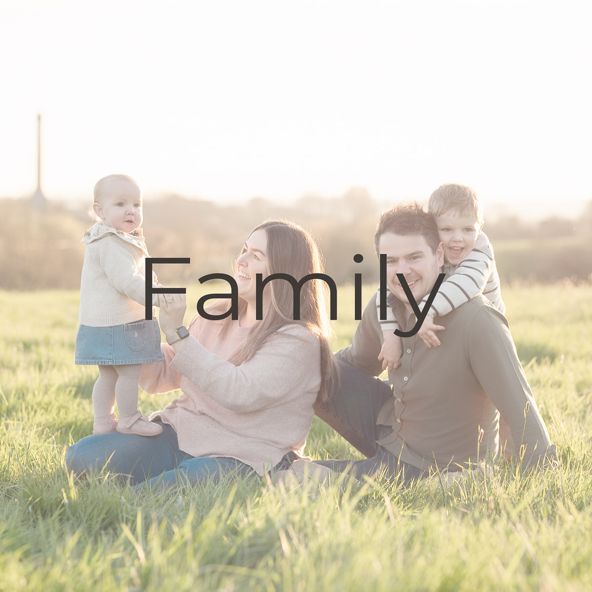 photograph of a family of four sitting on the grass on the common in Chipping Norton taken by this family photographer in Oxfordshire