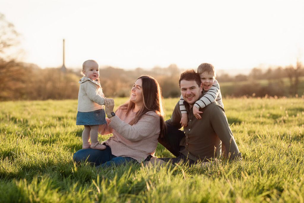 Family sitting together on the common in Chipping Norton at sunset
