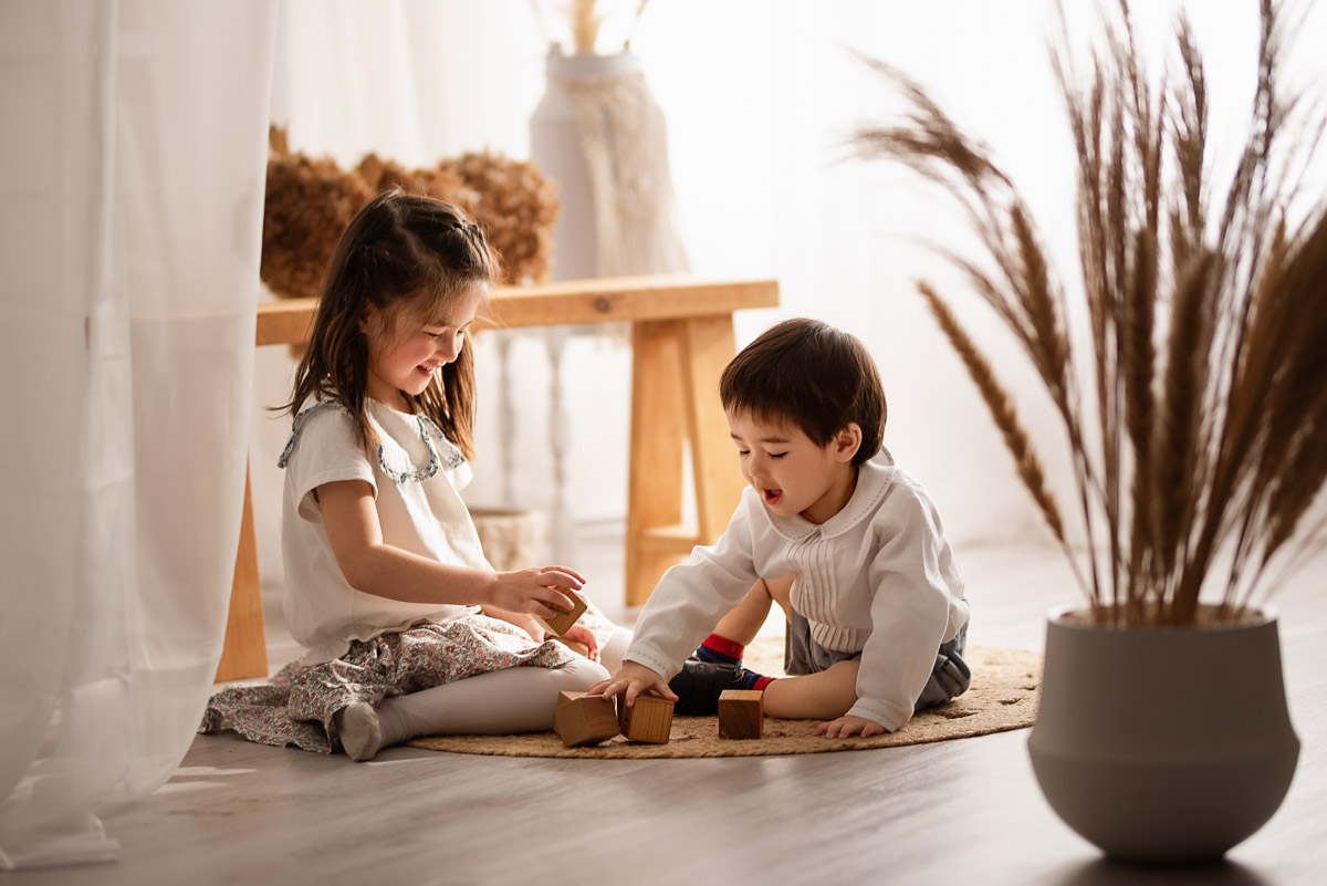 Two children play with wooden stacking blocks for a candid shot by their family photographer