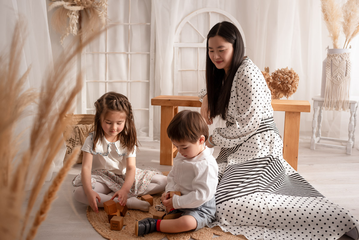 Mummy looks on as her children play with blocks during their family photography session in Oxfordshire